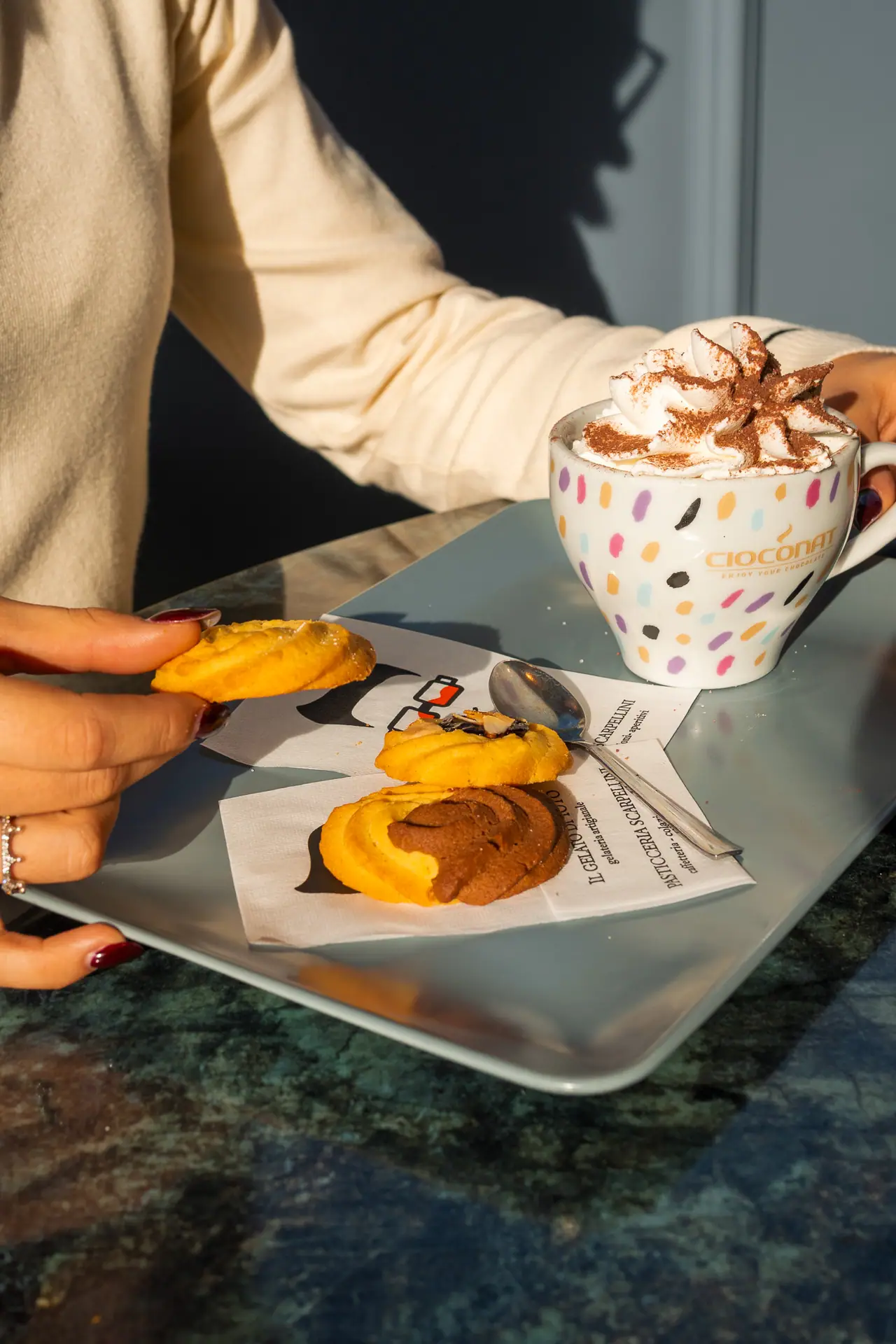 Cappuccino con panna e un cornetto al tavolo, luce del mattino