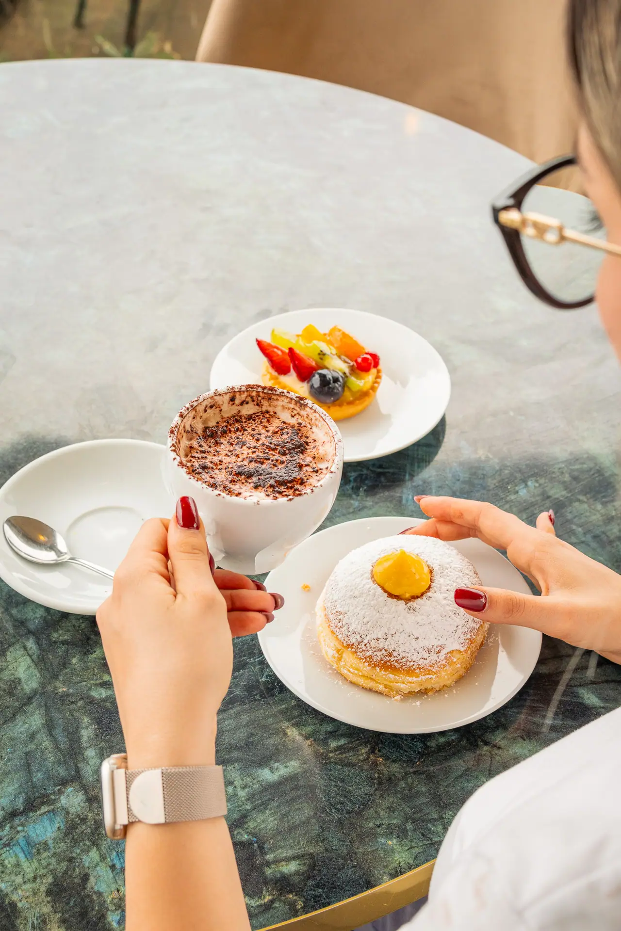 Colazione al tavolo verde: cappuccino, crostatina alla frutta e bomba alla crema