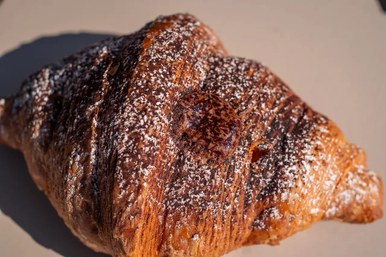 Cornetto al burro con zucchero a velo su un cartoncino crema