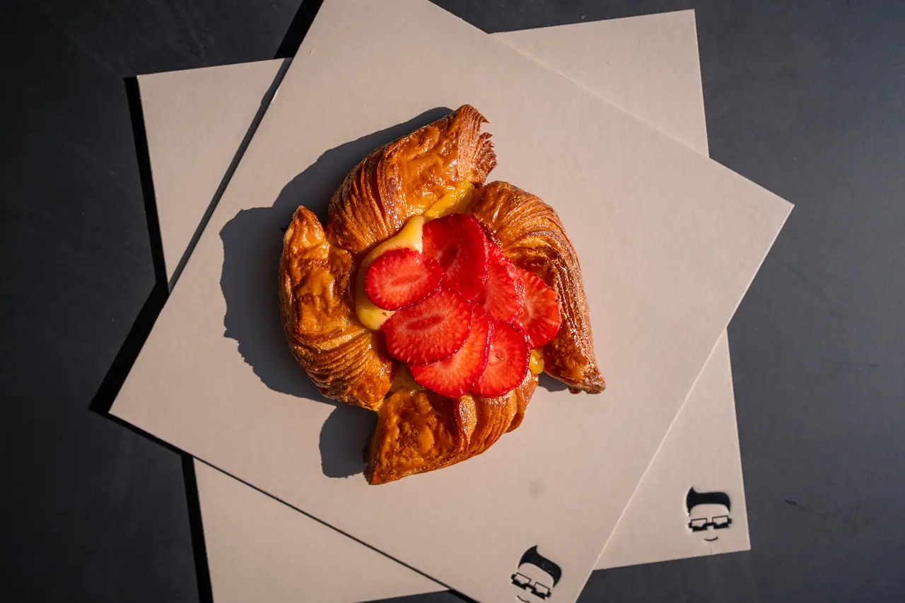 Cornetto con crema e fragole fresche su un cartoncino crema