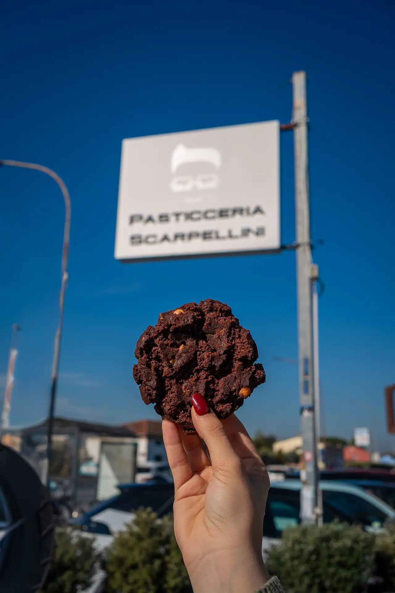 Un biscotto al cioccolato alzato davanti all'insegna della pasticceria
